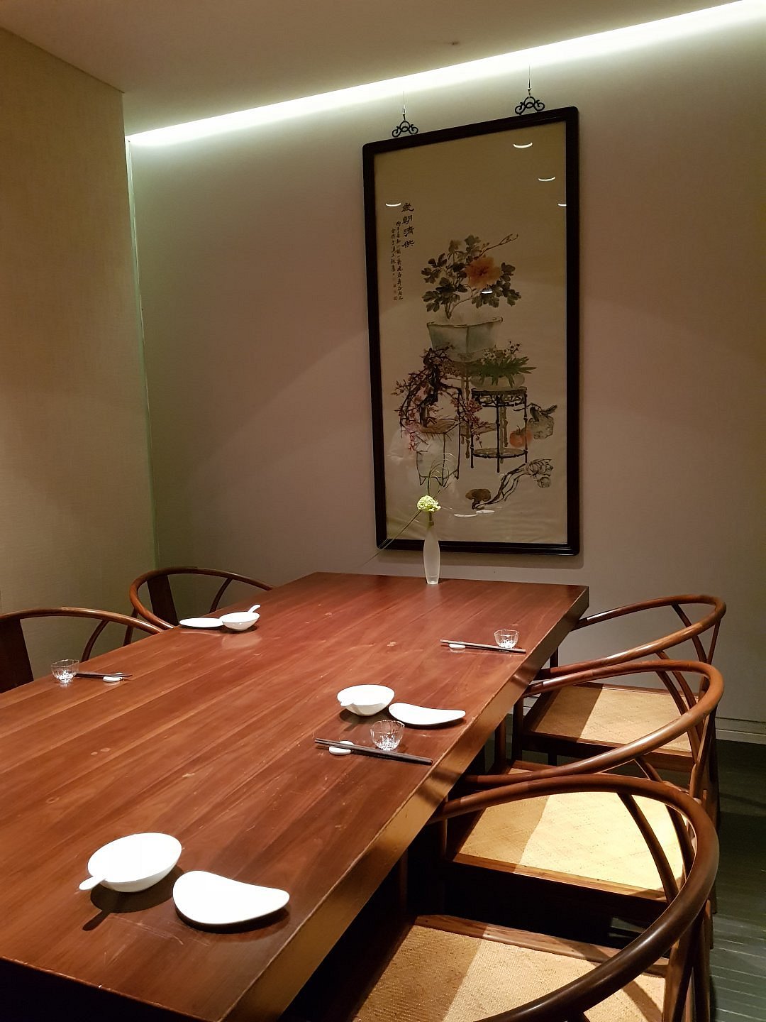 The serene dining room — dark wood, calligraphy, a single orchid on each table