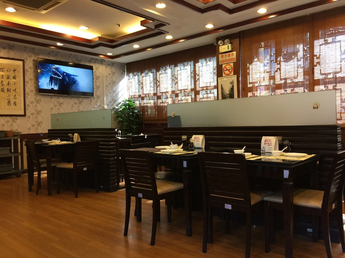Inside the bustling dining room — bamboo steamers tower behind the counter, fragrant with freshly made dumplings