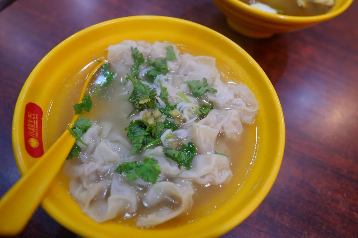 Cross-section: thin-skinned pork wontons in aromatic broth, the classic companion to shengjianbao